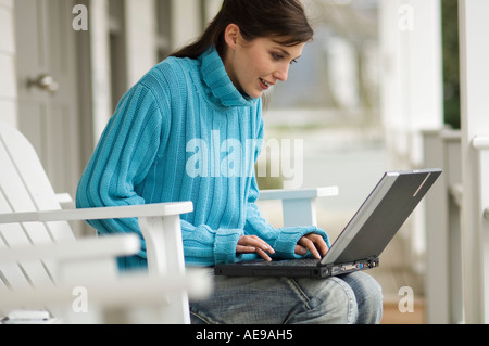 Young woman sitting on a chair, using a laptop computer, outdoors Stock Photo