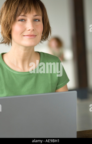 Young woman using laptop computer, looking at the camera Stock Photo