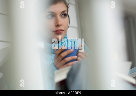 Young thinking woman holding cup Stock Photo
