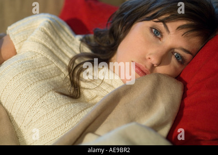 Young woman lying on a sofa, looking at the camera, close-up Stock Photo