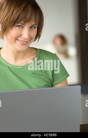 Young woman using laptop computer, smiling for the camera Stock Photo