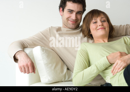 Couple lying on a sofa, smiling for the camera Stock Photo