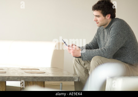 Man sitting on a sofa using a mobile phone Stock Photo