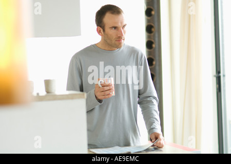 Man standing in the kitchen, holding mug Stock Photo