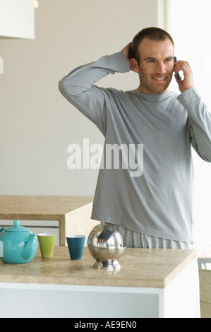 Man standing in the kitchen, using a mobile phone Stock Photo