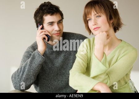 Couple sitting in living-room, man using a mobile phone Stock Photo