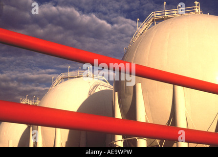 A graphic shot of red pipes in front of gas storage tanks Stock Photo