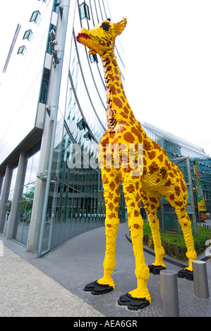 large figure TOY Giraffe made of lego brick ahead of SONY CENTER BERLIN reflections glass building front facade
