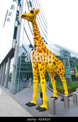large figure TOY Giraffe made of lego brick ahead of SONY CENTER BERLIN reflections glass building front facade