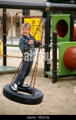 A 7 year old BOY plays on a tire swing MR Stock Photo
