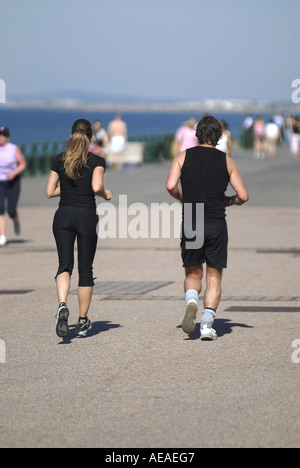 A MAN WOMAN OUT RUNNING ON THE PROMENADE HOVE UK SHOT FROM BEHIND Stock Photo