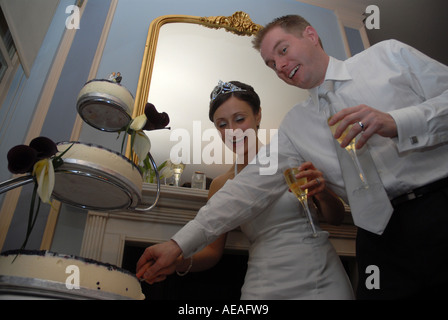 Bride and groom cut their wedding cake at their wedding reception at Kettners restaurant Soho London Stock Photo