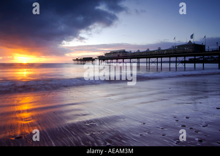 Dawn on the foreshore at Paignton South Devon with the Victorian Pier in the background and the sun rising in a cloudy sky Stock Photo