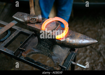 A hammer and a red hot horseshoe on a farriers anvil. England, UK Stock Photo