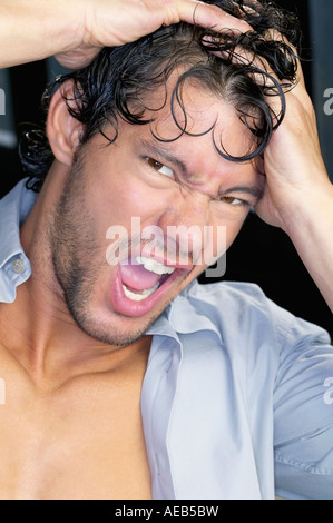 Close up of young man yelling with hands on head Stock Photo