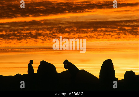 A couple taking a photograph at sunset at Castlerigg Stone circle, Keswick, Lake District, UK Stock Photo