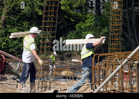 Construction workers on building site carrying materials, Milton Keynes, UK. Stock Photo