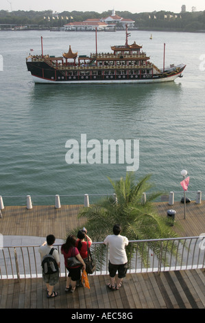 Tourists at the  VIVO City Habour Front looking at Chinese junk and Sentosa Island in Singapore Stock Photo