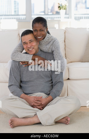 Middle-aged African couple hugging on sofa Stock Photo