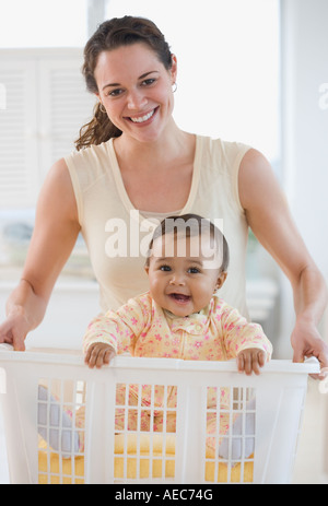 Hispanic mother carrying baby in laundry basket Stock Photo