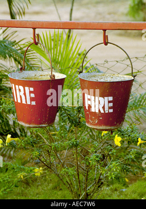 Two red buckets filled with sand and painted Fire hanged serially near a petrol bunk in Kerala India Stock Photo