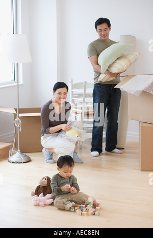 Asian parents watching baby play with blocks on floor Stock Photo
