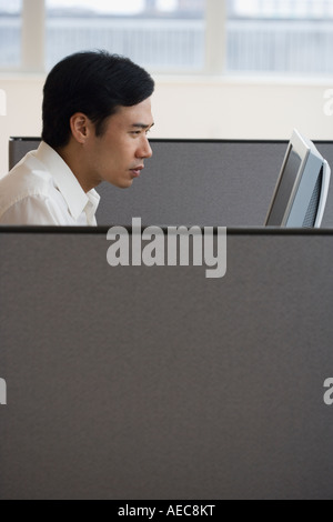 Asian businessman working in cubicle Stock Photo