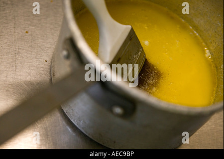 Melted butter and brush in a tin saucepan on a metal kitchen surface Stock Photo