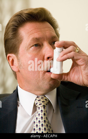 Man using inhaler to treat his asthma condition. Stock Photo