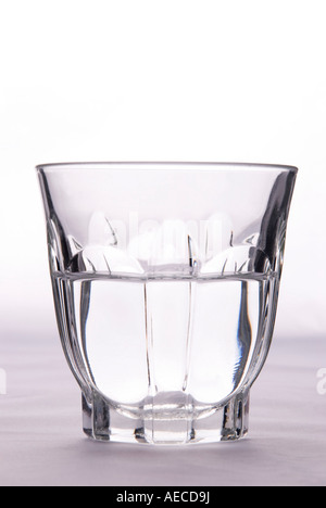 A glass half full or half empty to illustrate the idea of pessimism or optimism on a plain background Stock Photo