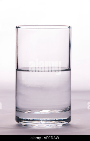 A glass half full or half empty to illustrate the idea of pessimism or optimism on a plain background Stock Photo