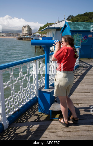 Woman using a telescope on the pier at Llandudno Wales UK Stock Photo