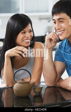 Asian couple having tea and using cell phone Stock Photo