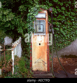 Vintage old redundant disused retro Avery Hardall petrol pump not in use covered in overgrown ivy at a gas station in Powys Wales UK  KATHY DEWITT Stock Photo