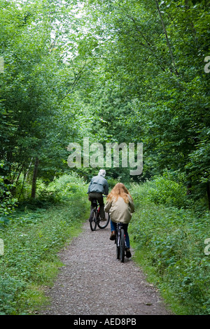 Two adults cycling on a sustrans cycle path made from a disused railway line Llanfoist Wales UK Stock Photo