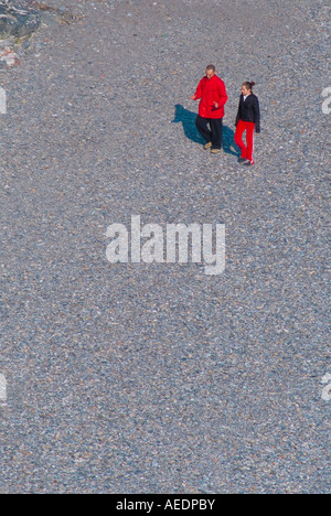 Couple wearing red and black on sandy beach Stock Photo