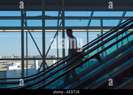 Man on escalator in airport terminal Stock Photo