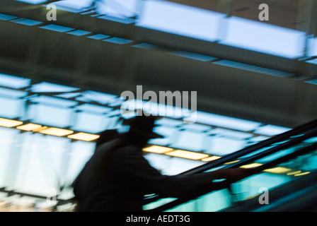 Man on escalator in airport terminal Stock Photo