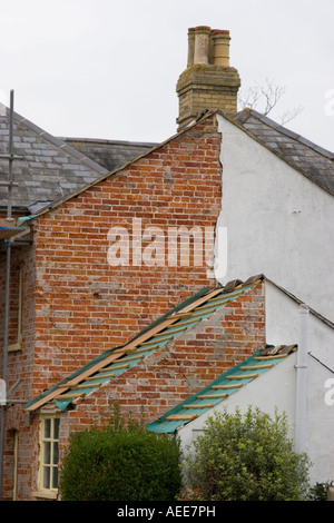 Red brick revealed under rendering removed from gable end of house Stock Photo