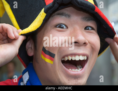 A Japanese football fan in good mood posing with hat and sticker in German national colours Stock Photo
