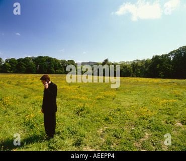 man standing talking on a cellphone in a green field Stock Photo