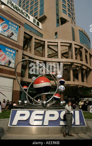 A business man talks on his mobile beside a Pepsi sign outside a modern shopping centre on Nanjing Road Stock Photo
