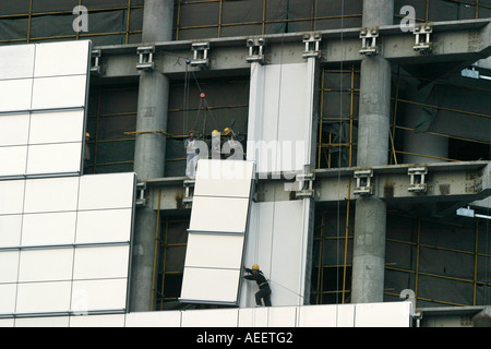 Shanghai China Construction workers positioning cladding panels on a new sky scraper being built in the centre of Shanghai Stock Photo
