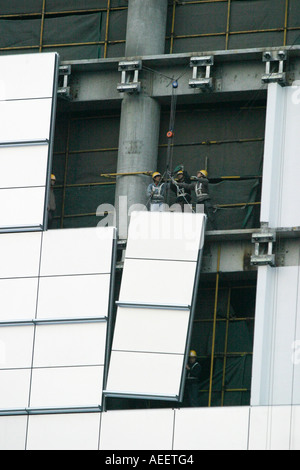 Shanghai China Construction workers positioning cladding panels on a new sky scraper being built in the center of Shanghai Stock Photo