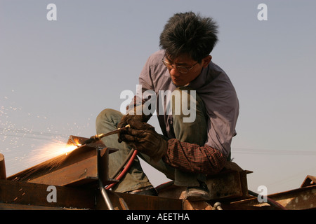 Shanghai China Construction crew member uses an oxyacetylene torch to remove a lifting tab from a girder Stock Photo