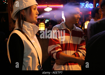 Young woman smoking  on the street outside one of the lively bars on the Maoming Road Shanghai Stock Photo