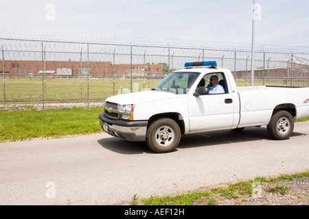 Patrol vehicle patrolling the outer perimeter fence at the Omaha Correctional Center Omaha Nebraska USA Stock Photo