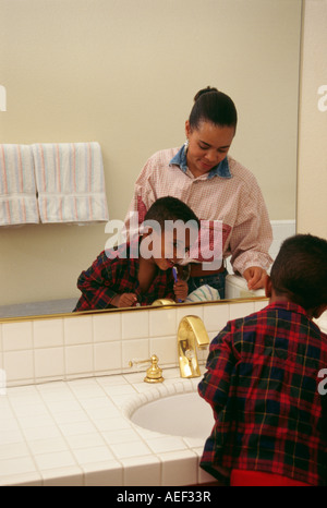 Boy 5-6 year old  brushing teeth holding toothbrush smiling rear view Stock Photo