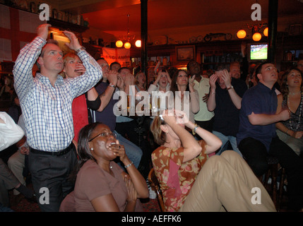 People cheering in pub while watching England world cup football match on large screen. Stock Photo