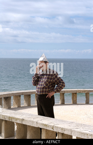 A portuguise man with paper hat answers his mobile phone whilst on a jetty in Albufera Portugal Stock Photo